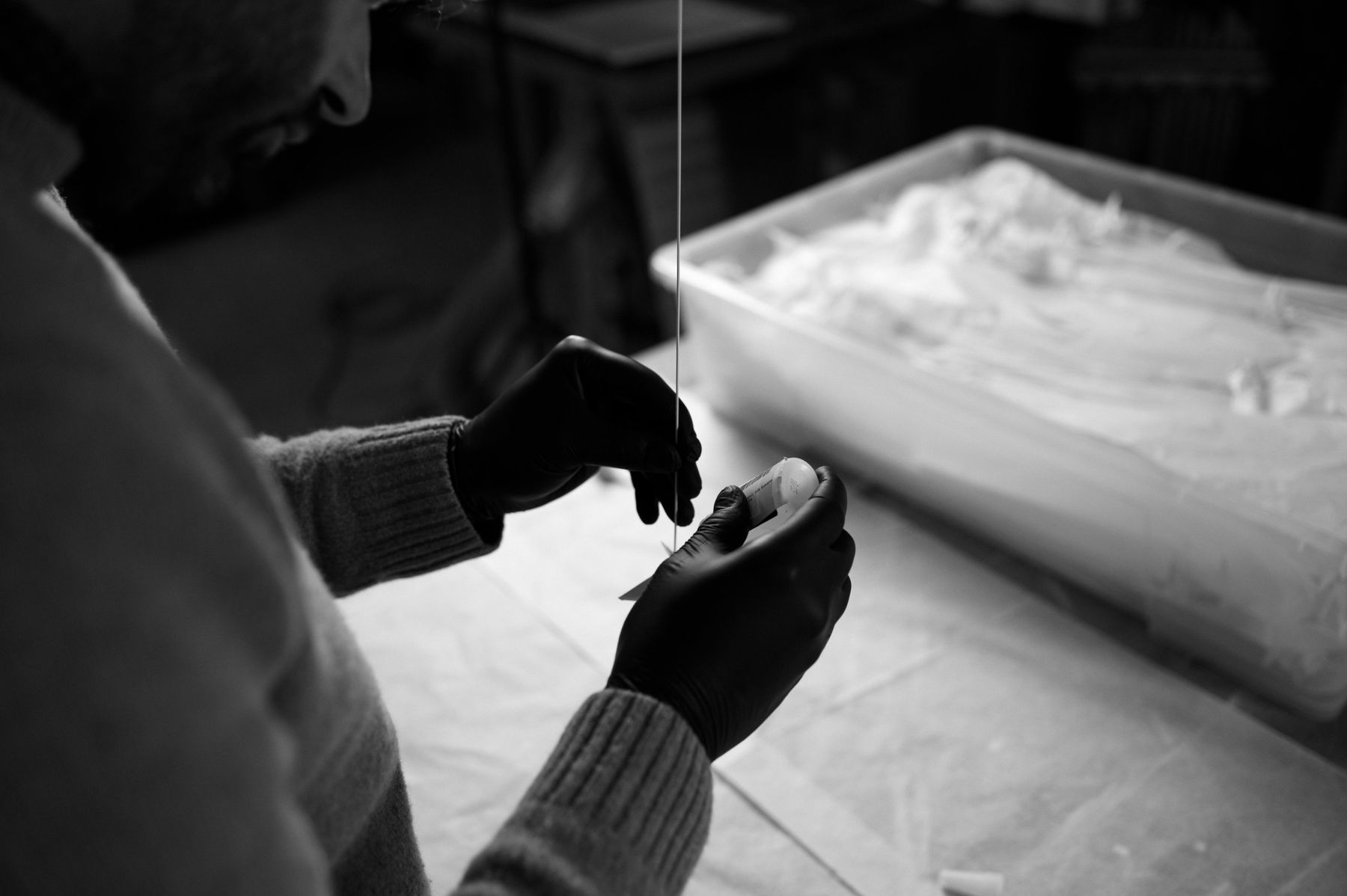 Photo noir et blanc de mains gantées fixant une grue sur sa tige.