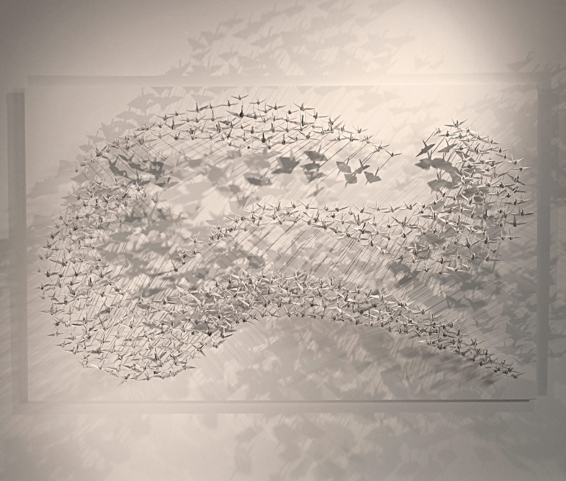 Murmuration 25, nuée de grues en papier blanc sur panneau.