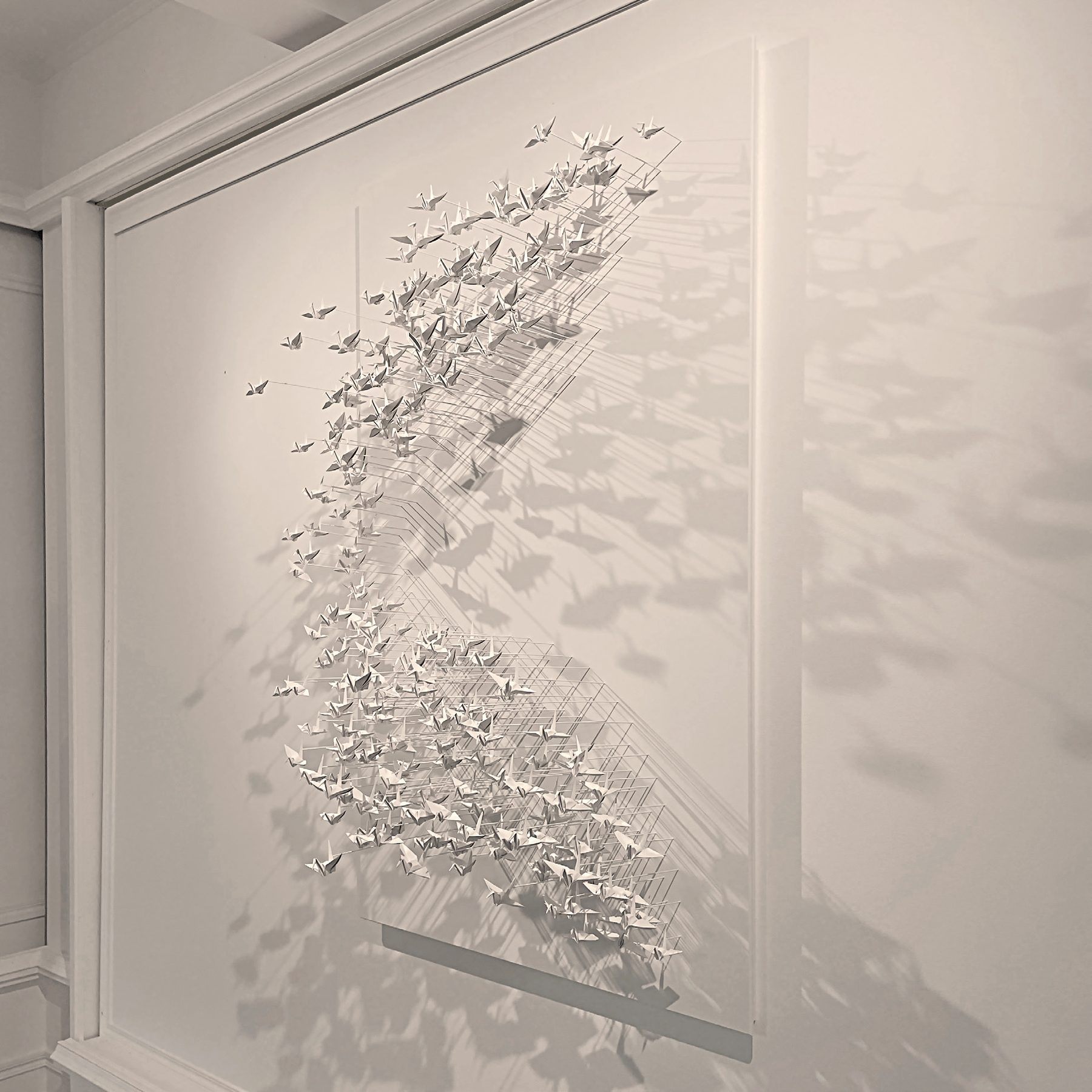 Murmuration 27, nuée de grues en papier blanc sur panneau.