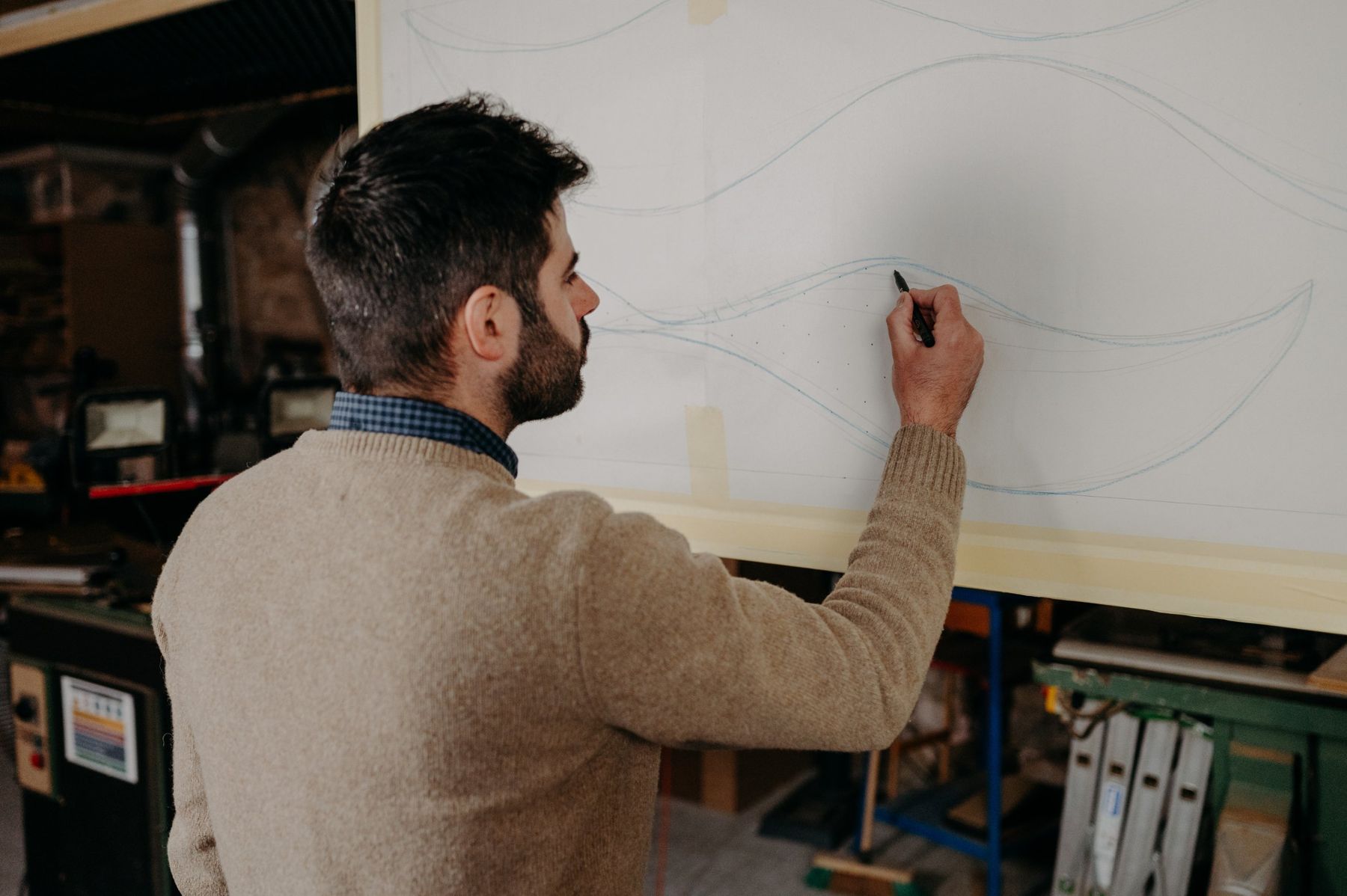 Benjamin Gaumard trace des courbes au crayon sur un grand panneau.
