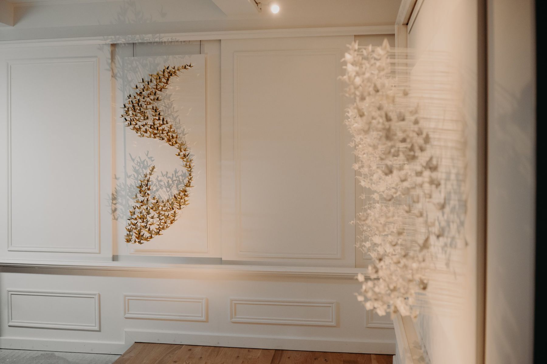 Une Murmuration en laiton au mur, une Murmuration en papier au premier plan.