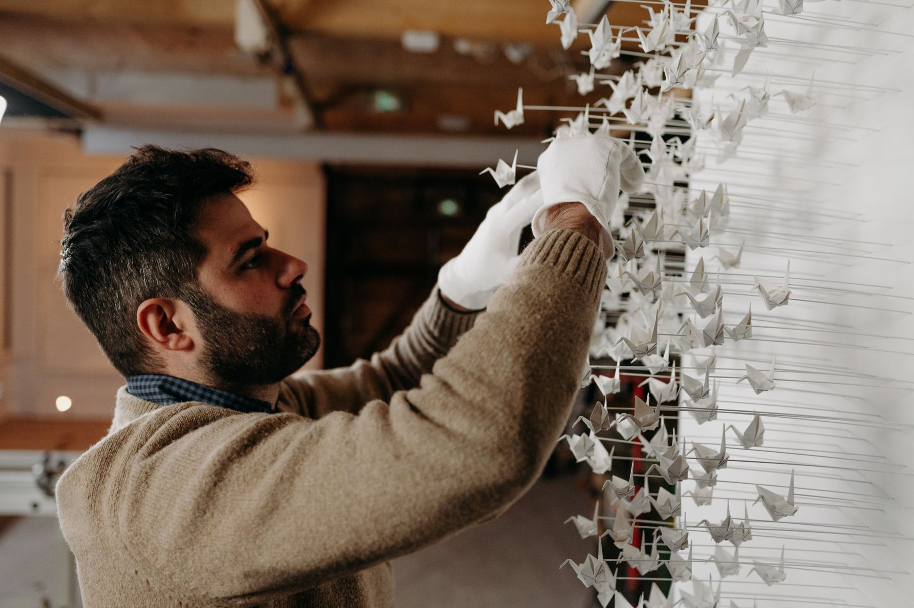 Benjamin Gaumard pose des grues en papier avec des gants blancs.